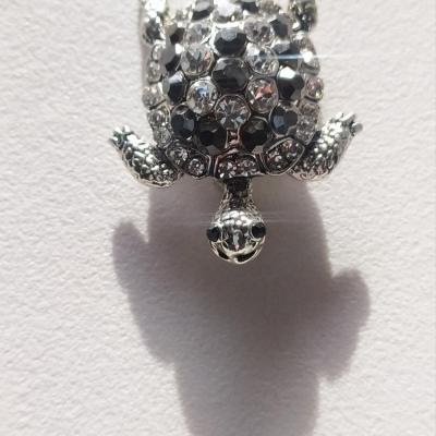 Broche tortue argentée et strass noir-blanc.